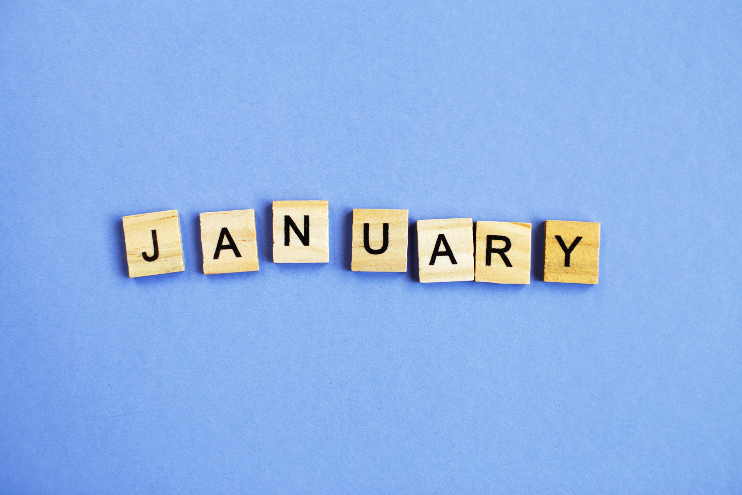 inscription January made by wooden cubes on a veri peri purple background